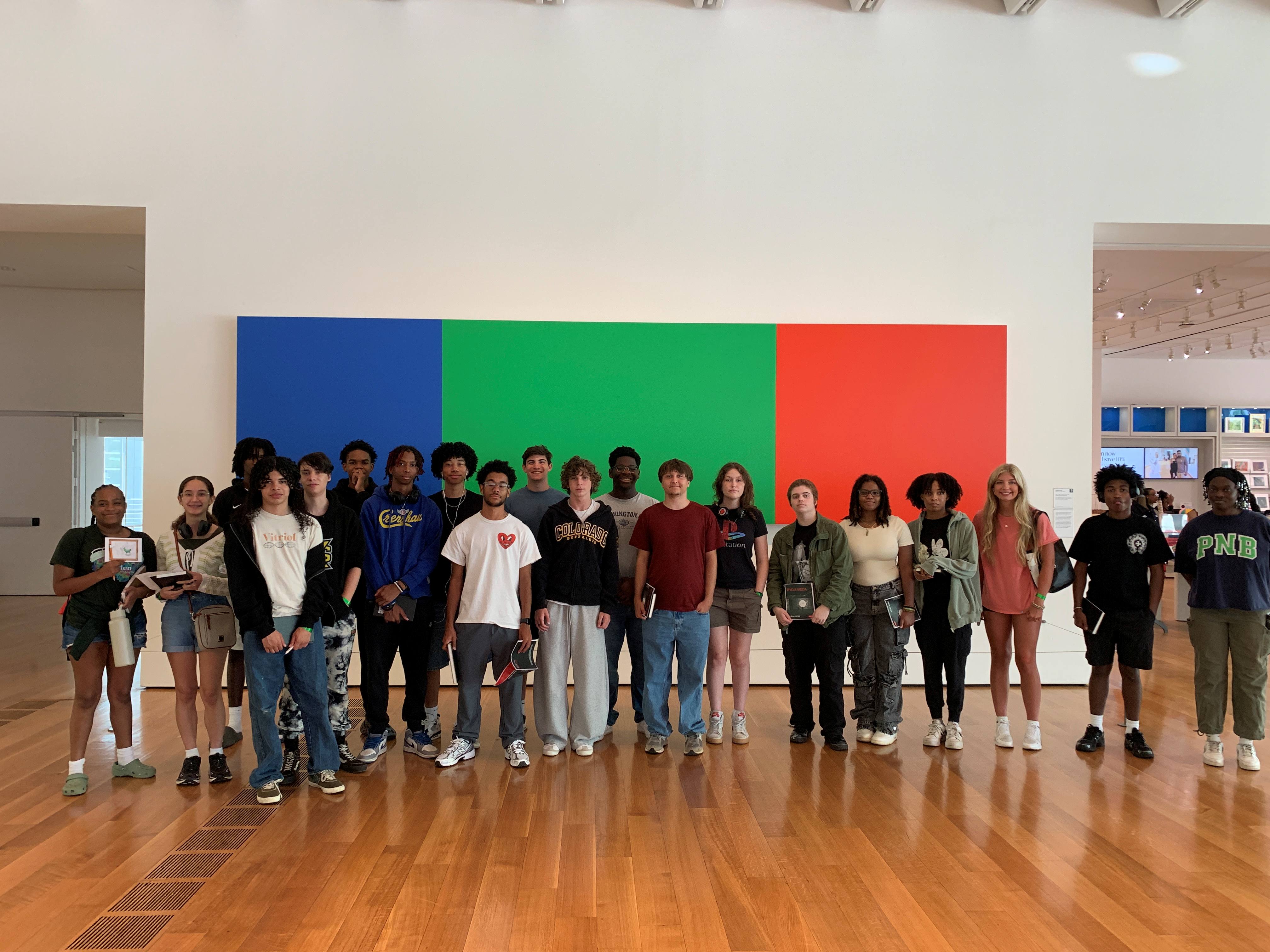 Summer Academy students posing for a group photo in front of a piece of color-blocked art. 