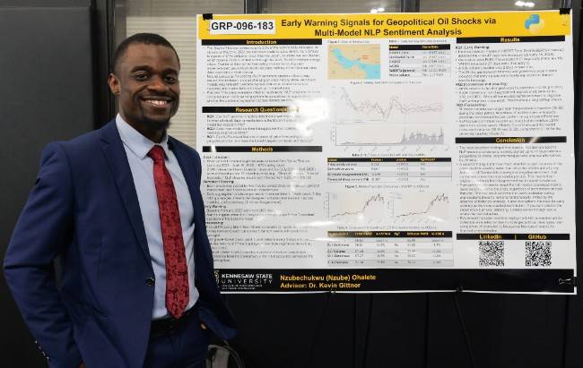 Nzube smiles at ccamera in front of his research 