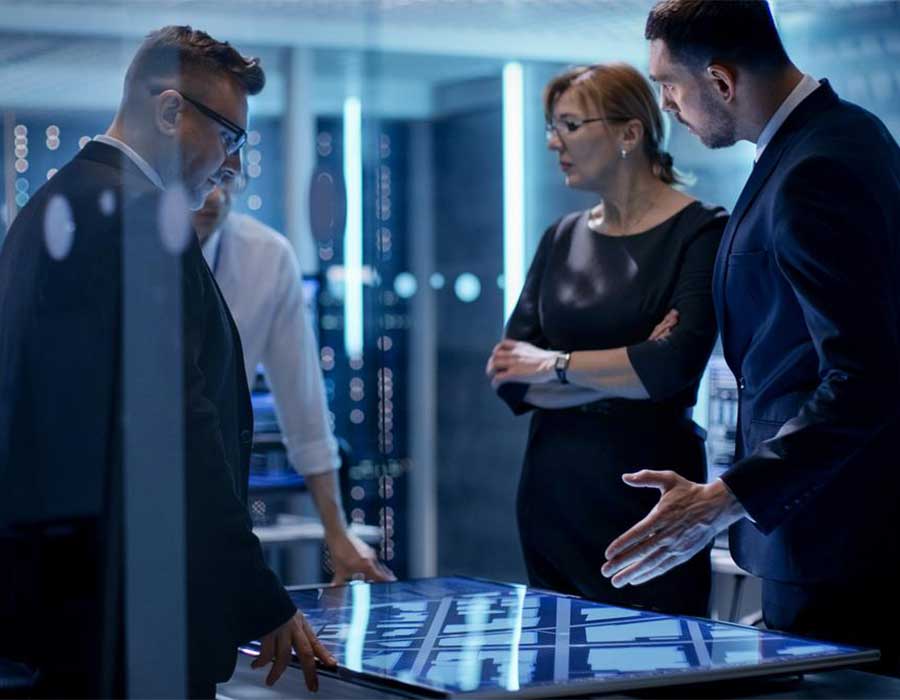 Three people standing around a tabletop computer