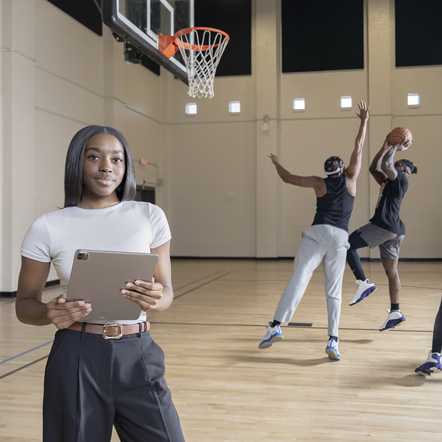 Data analyst Anaya Tention studies sports injury data while watching a basketball game.
