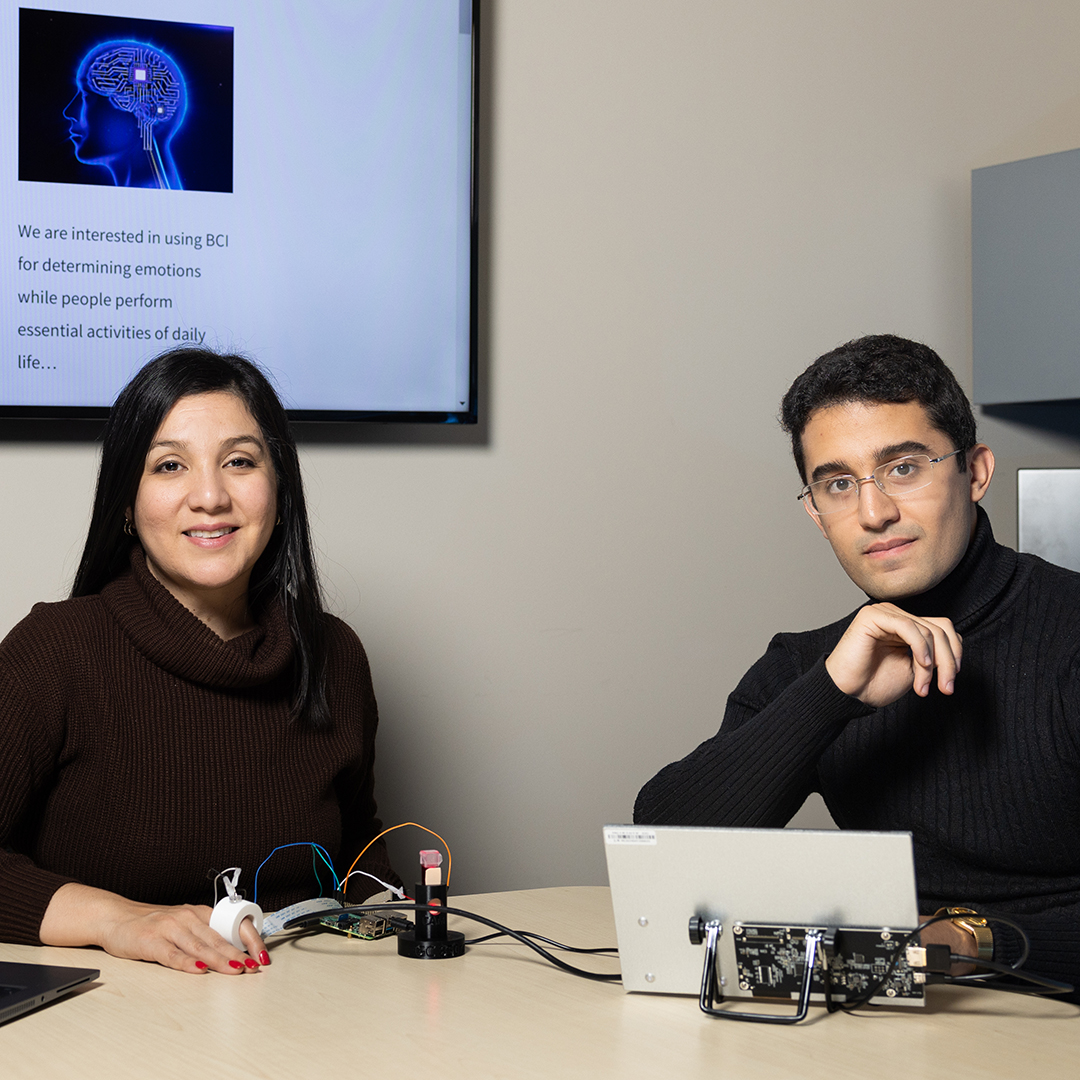female and male students posing next to eachother by computers