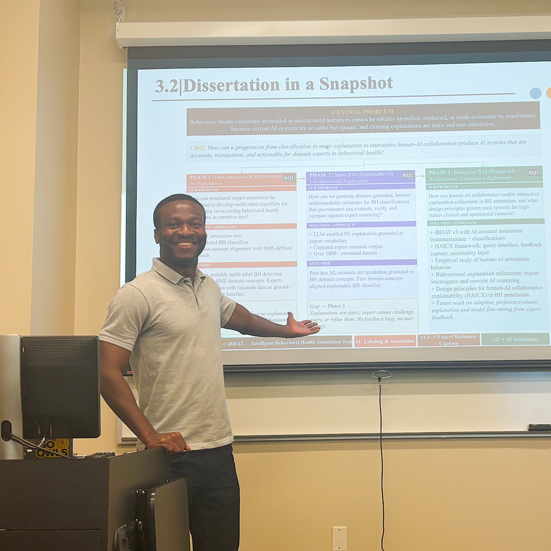 african american male smiling as he gives presentation and points to board