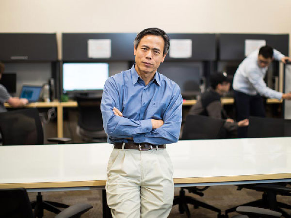 Dan Lo posing with his arms crossed, in front of a table.