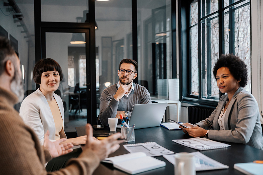 four business professionals having a meeting on a glass walled board room