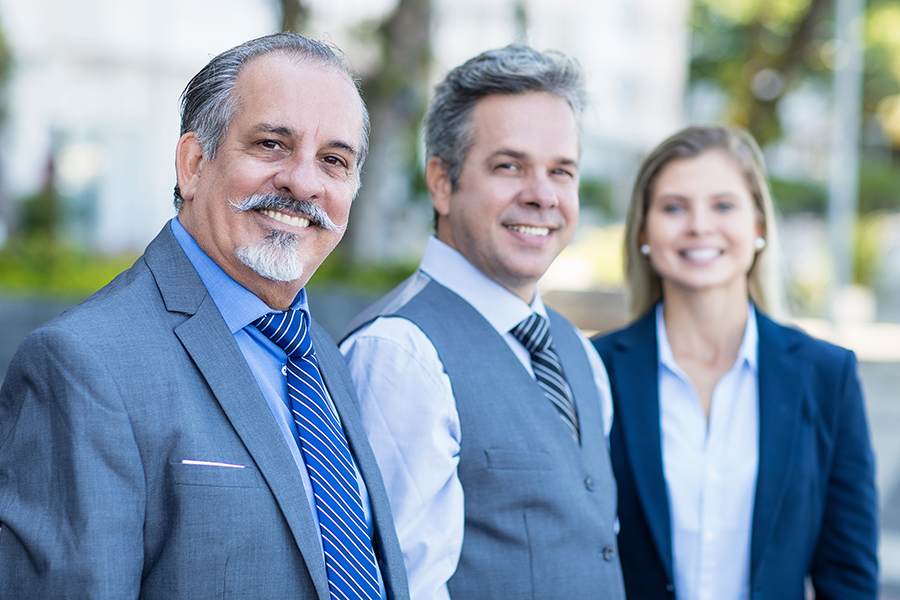 three people standing together, dress in business attire. 