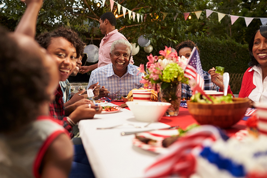 a family sharing a meal at a picnic table during the 4th of July