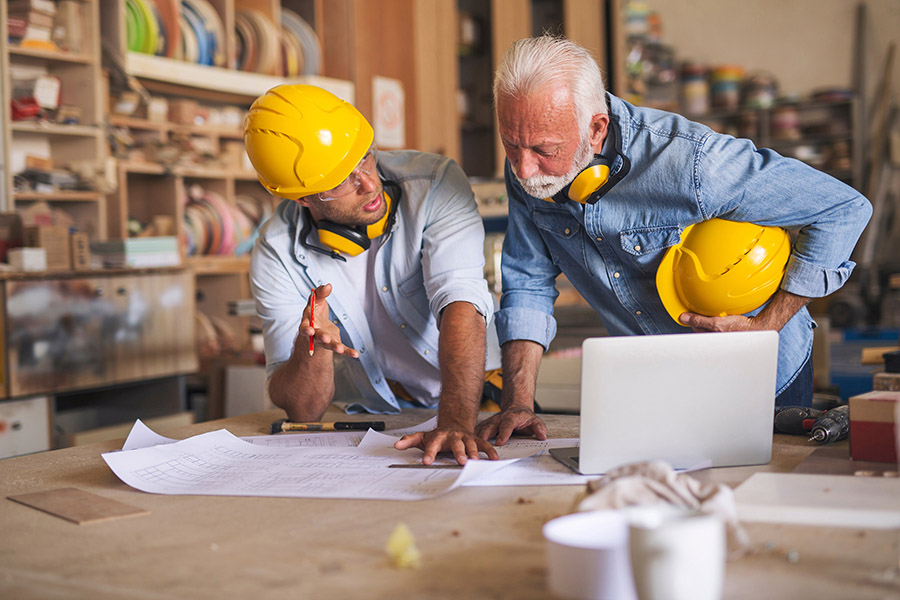 2 men looking over blue prints.