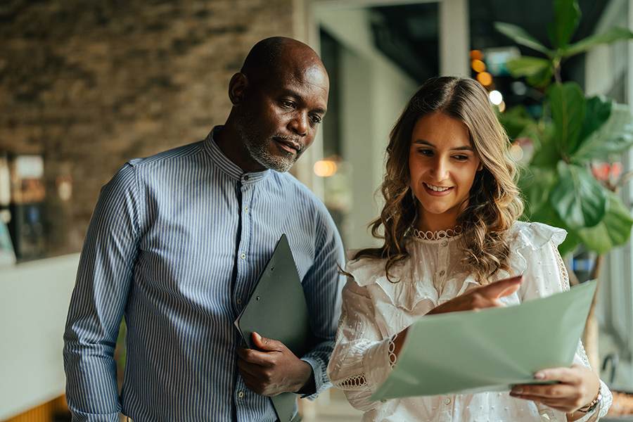 a man and a woman look over a file folder