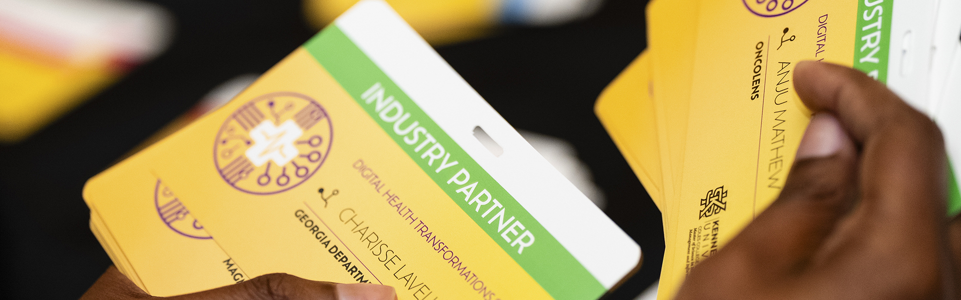 Professional holding a conference registration badge that reads, "industry partner."