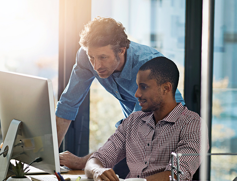 two men looking over information on a computer.