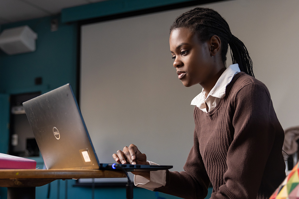 Young woman sits with a laptop on a table, studying.