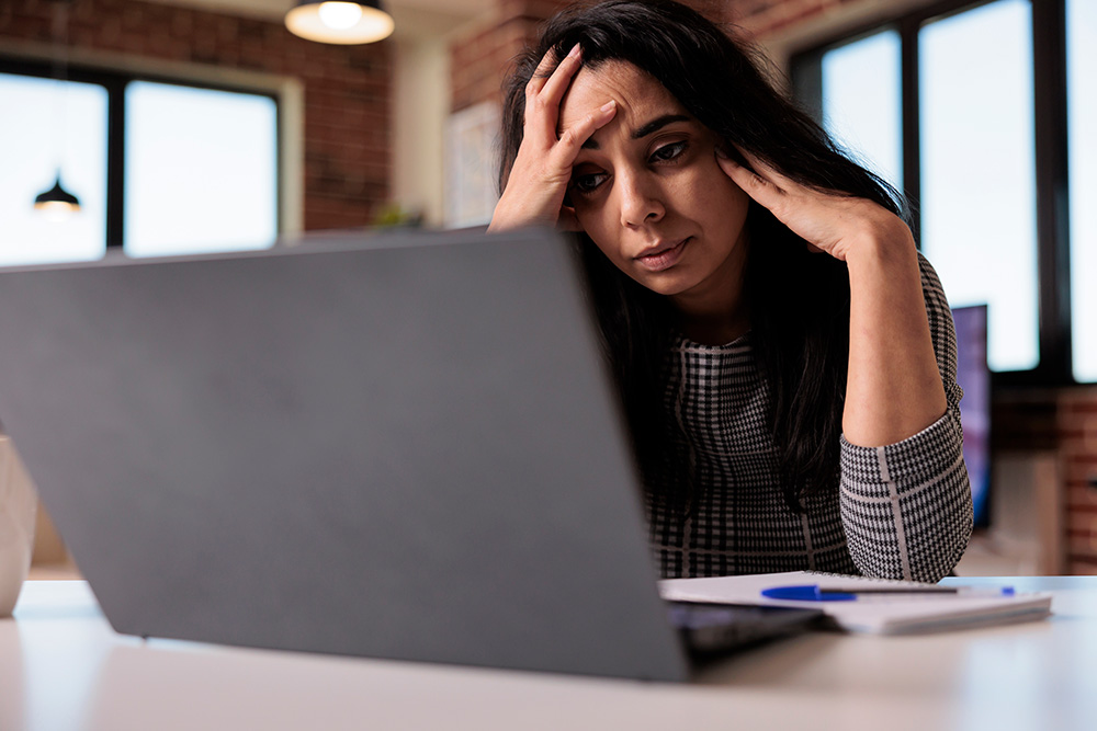 A distressed woman sits with her laptop