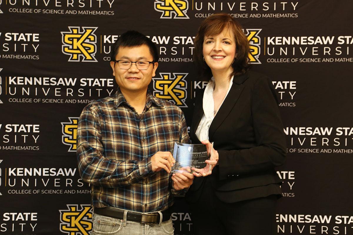  / ription
Photo of the Outstanding Early Career Faculty Award winner, Dr. Min Wang, Assistant Professor of Mathematics, (left) and Dr. Marla Bell, Interim Dean (right) 