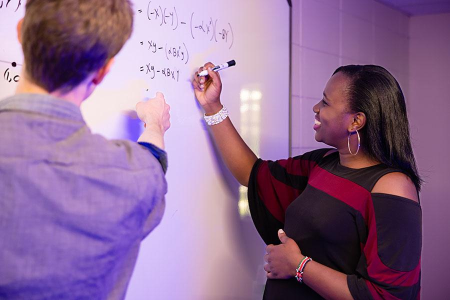 n A mathematics student writing an equation on a white board while a faculty member looks over. / n
A mathematics student writing an equation on a white board while a faculty member looks over.