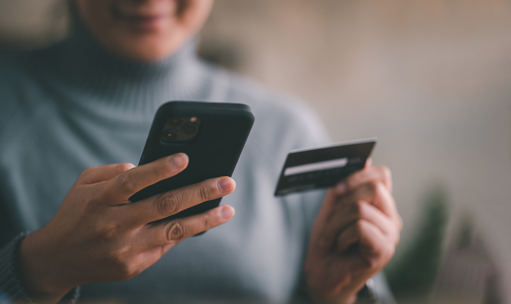 woman using credit card to pay by mobile phone