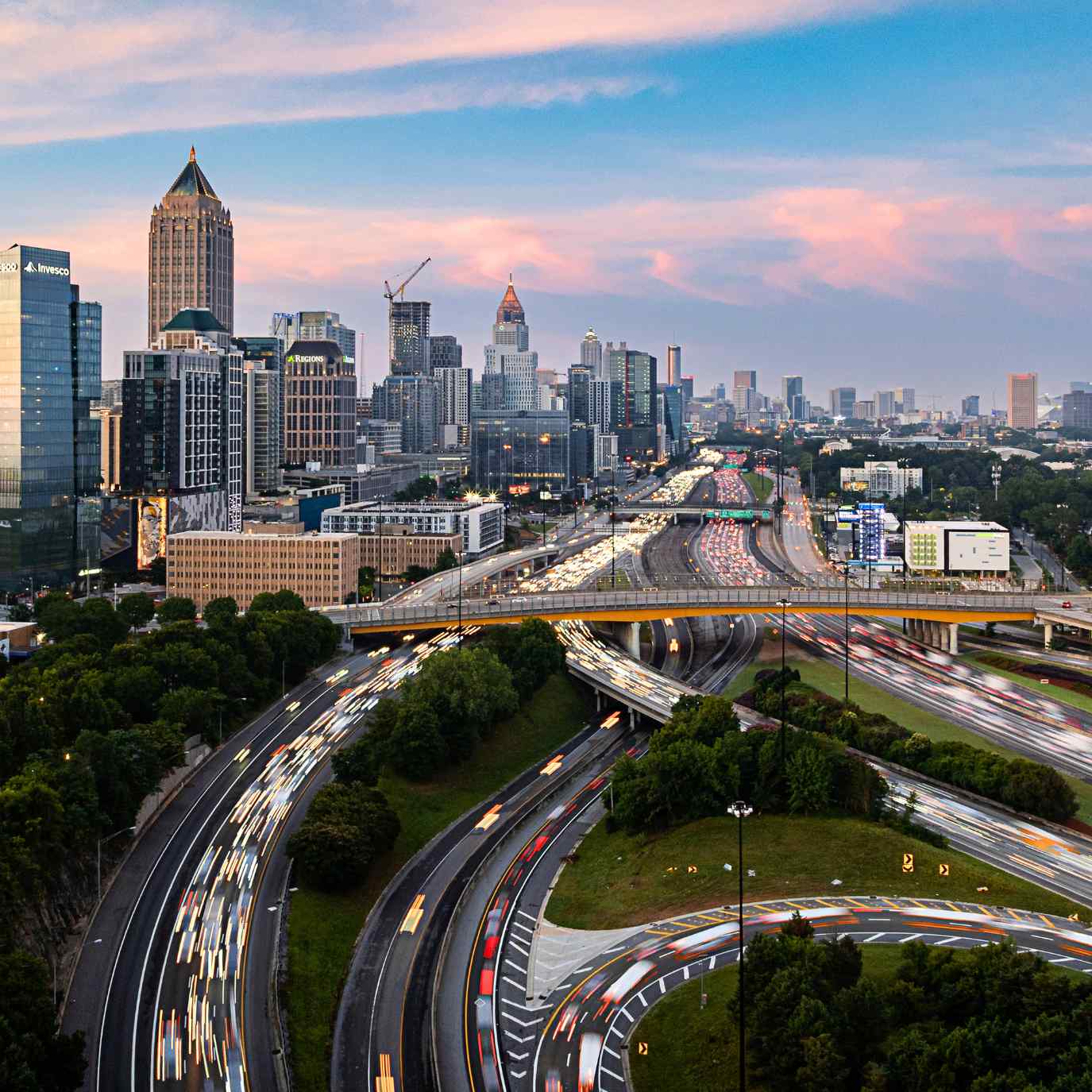 Atlanta skyline at dusk with heavy traffic on intersecting highways in the foreground.