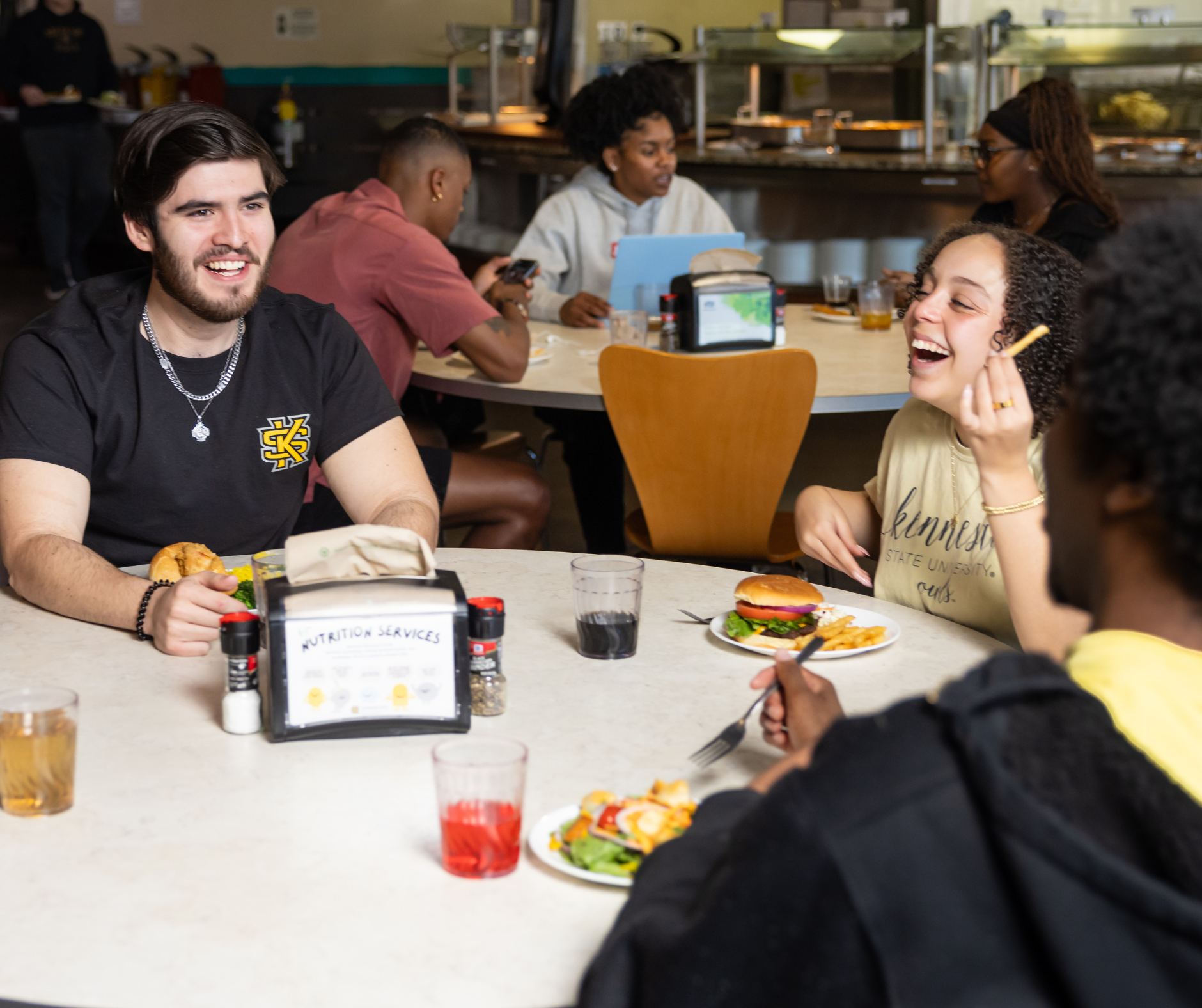 Group of students eating at a round table in the KSU Commons Dining Hall.