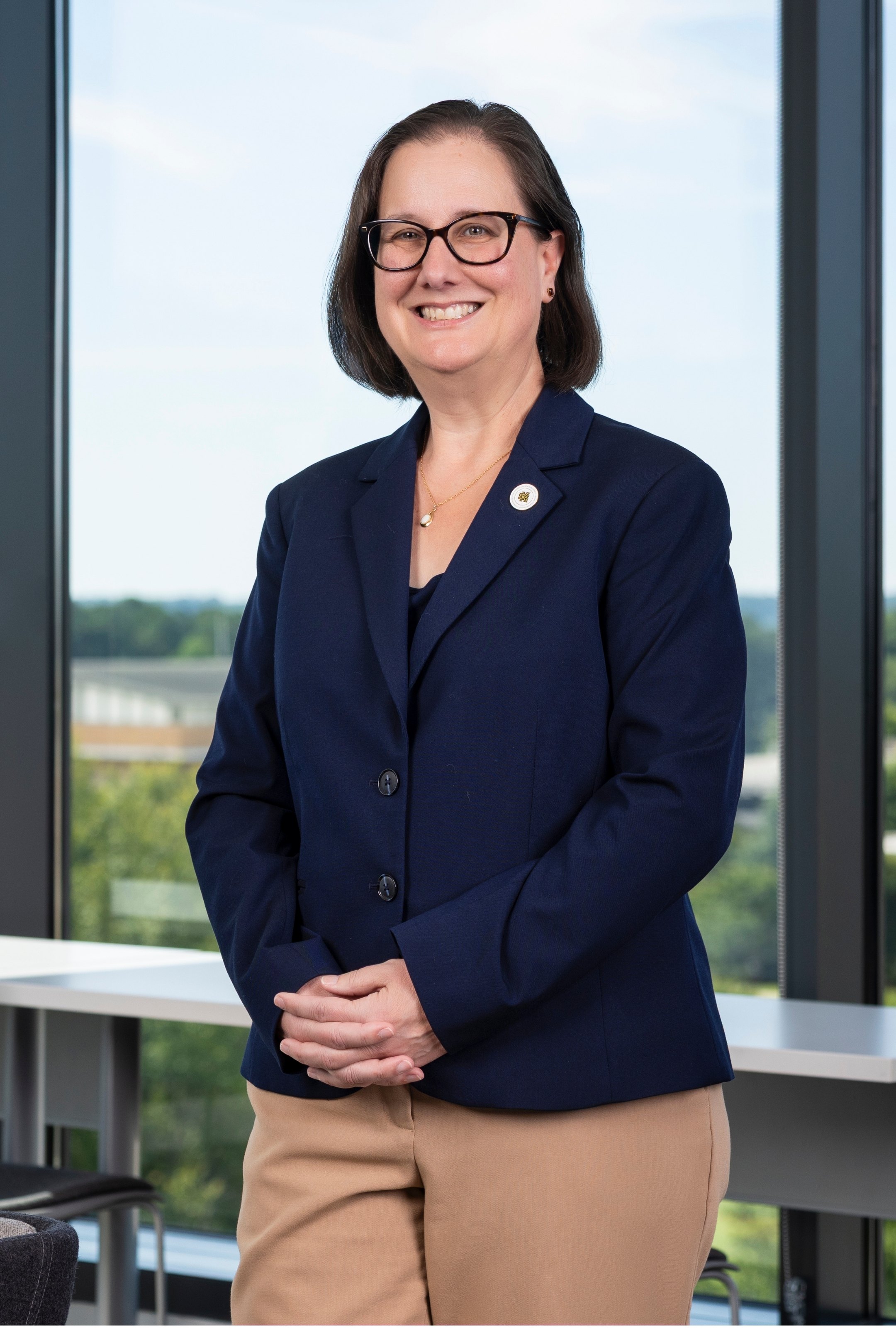 Dean Karen Kornweibel stands and smiles in the Kennesaw Honors Lounge in front of a window.