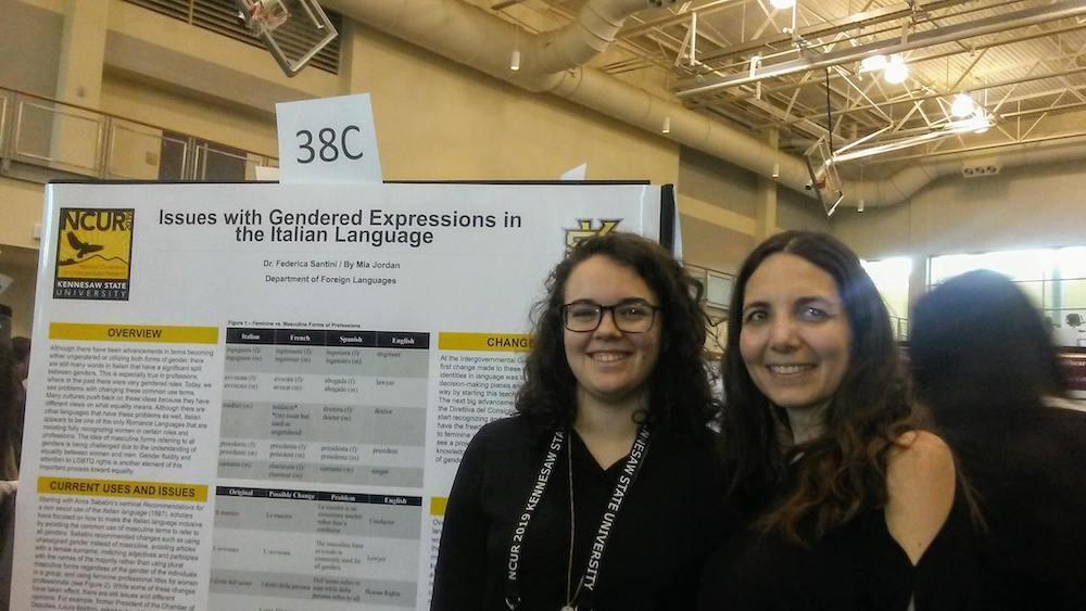 National Conference 2019 News / Two people stand smiling in front of a research poster titled "Issues with Gendered Expressions in the Italian Language" at an academic conference.