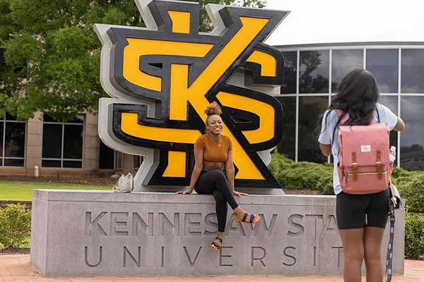 students taking picture on ksu logo on campus