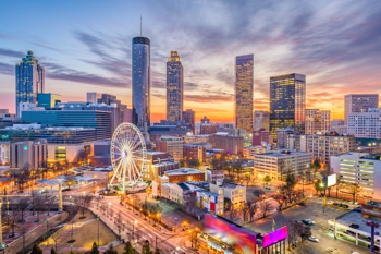 Atlanta skyline at sunset with a Ferris wheel and illuminated buildings.