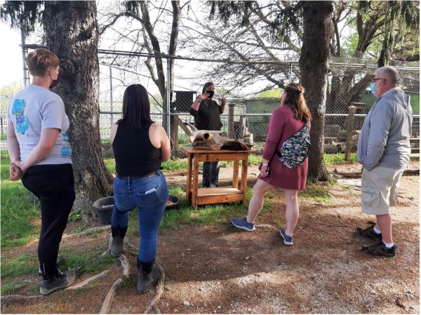 A group of people standing outside watching a presentation at Wolf Park