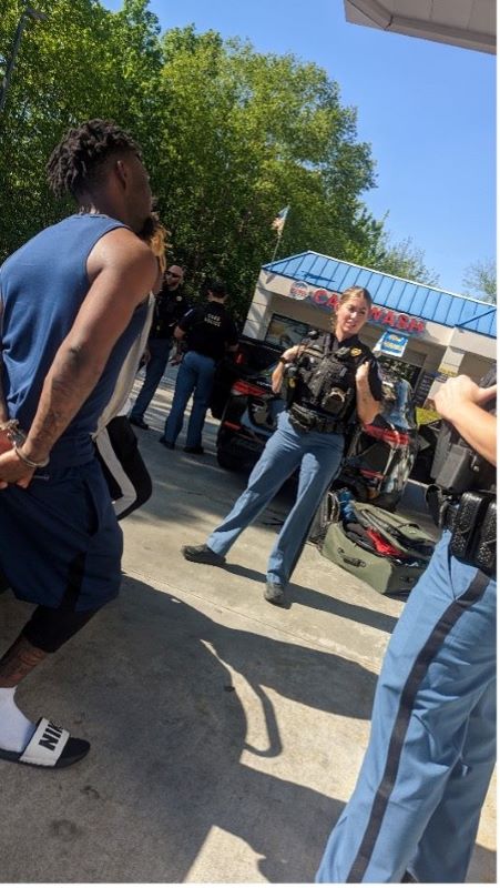 A group of students standing with two police officers in an outdoor setting.