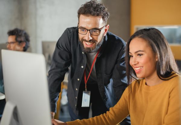 A smiling student and advisor collaborate at a computer.