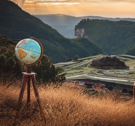 A globe on a stand, overlooking a mountain landscape.