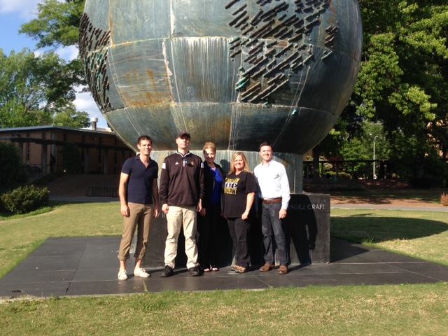 A group of people stand together in front of a large globe.
