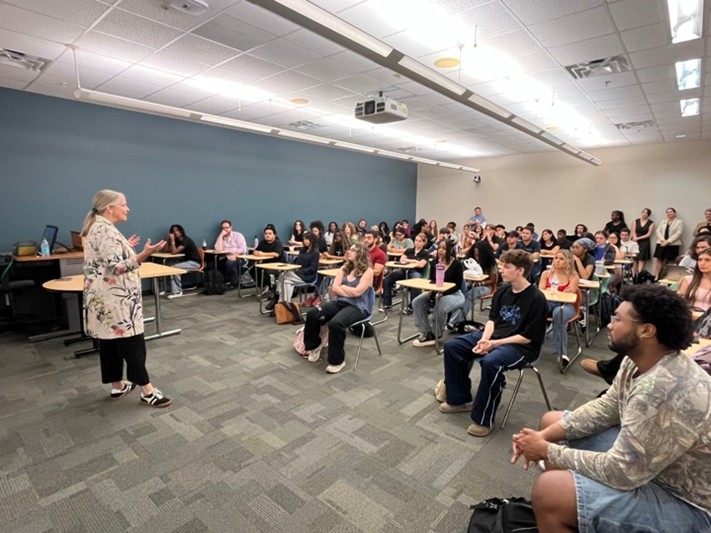 Representative Lisa Campbell speaks to students in a large classroom
