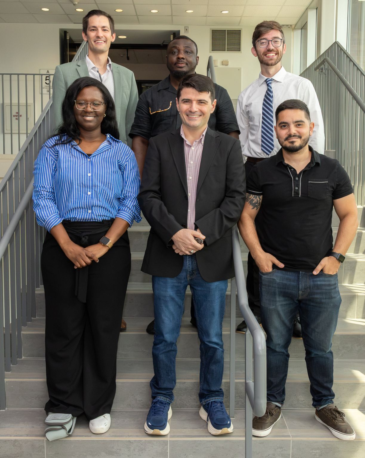 Six new SGIA faculty members pose on a staircase at Kennesaw State University after joining the school in Fall 2026.