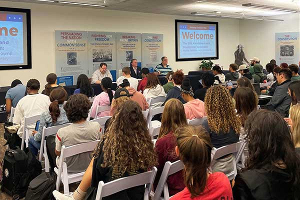 seated crowd facing panel speakers
