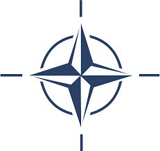 NATO emblem with a dark blue compass rose inside a circle on a white background.