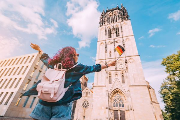 A student with a German flag in front of a historic church
