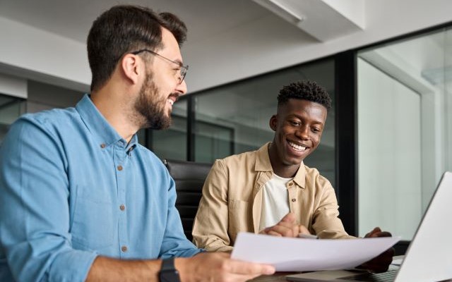 Two males looking over a document in an office setting.