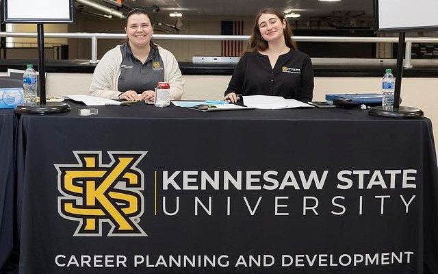 Two women seated at a check-in table for Kennesaw State University Career Planning and Development.