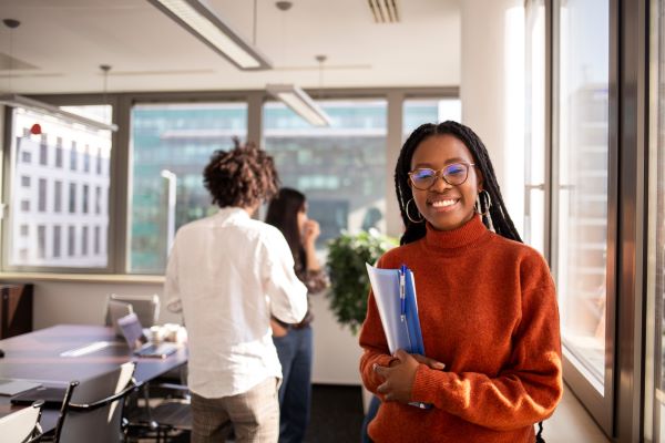 A smiling woman standing in an office holding a folder