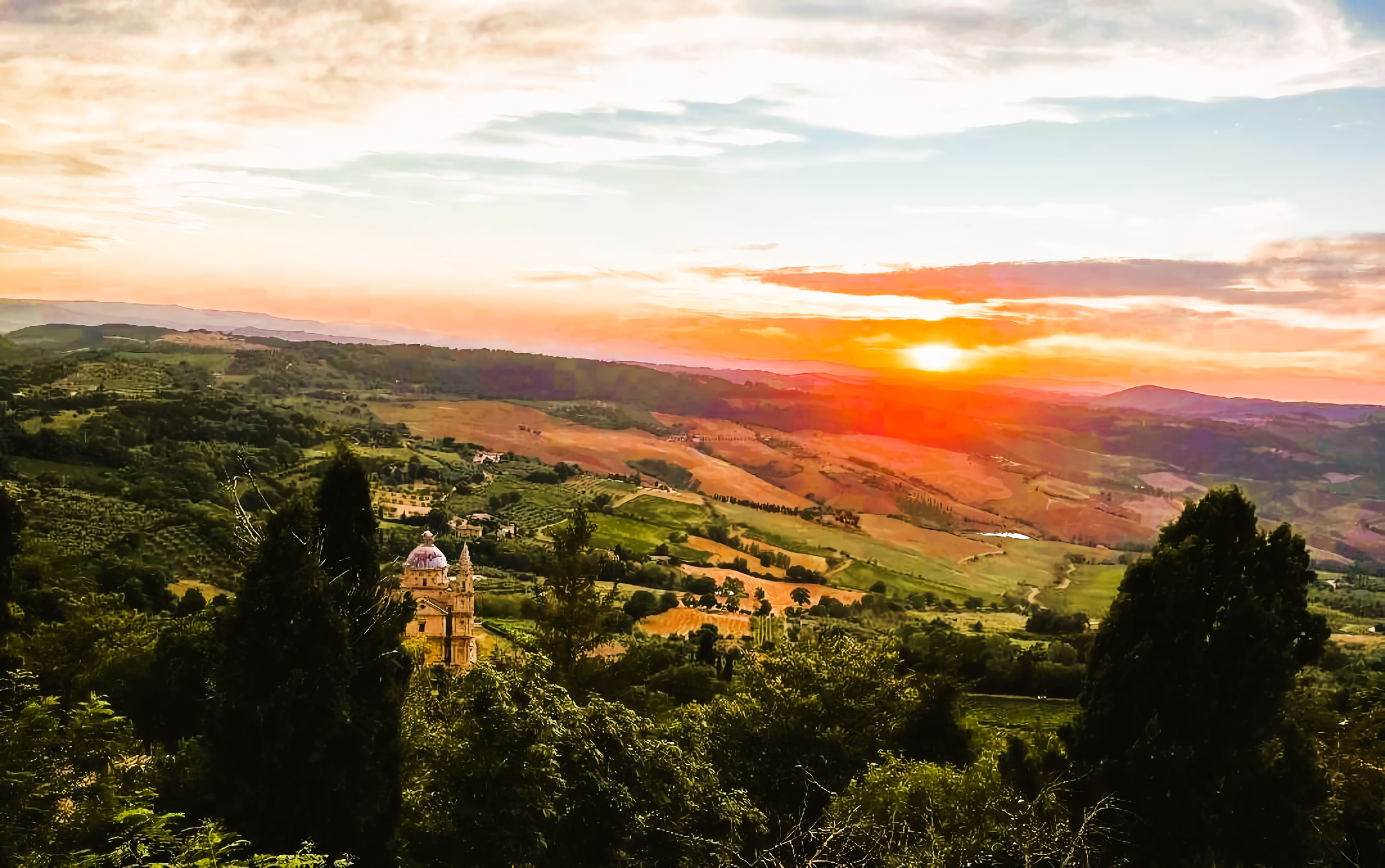 View of Montepulciano and the surrounding Tuscan countryside at sunset.