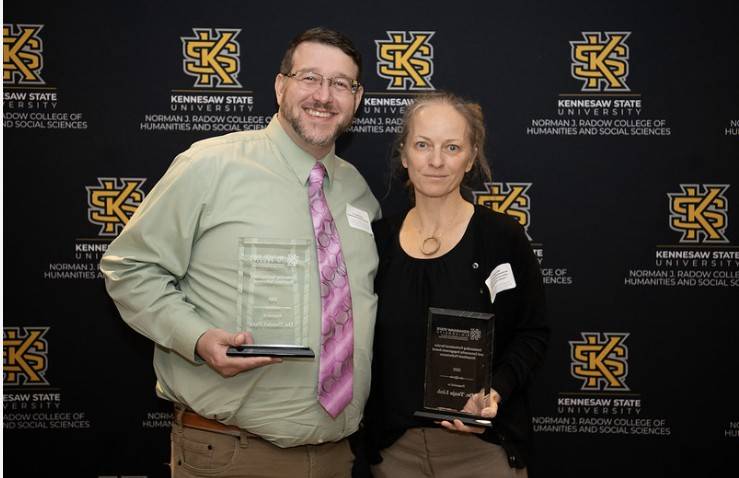 Dr. Farr (left) and Dr. Link (right) posing with their awards in front of KSU background