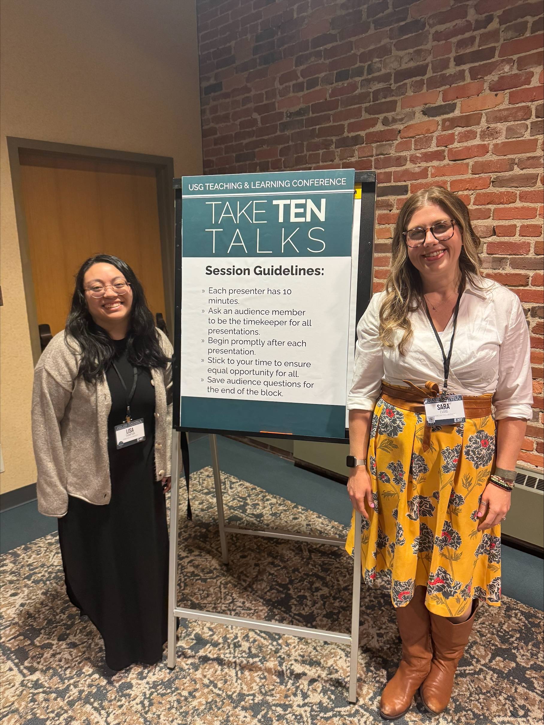 Professors Lisa Thompson (left) and Sara Evans (right) standing with Take Ten Talk Sign