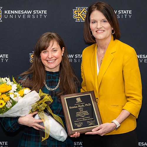 Dr. Kristina Hook of KSU, holding an award and flowers.