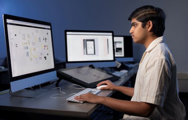 Student working on UX/UI design projects at a computer workstation.