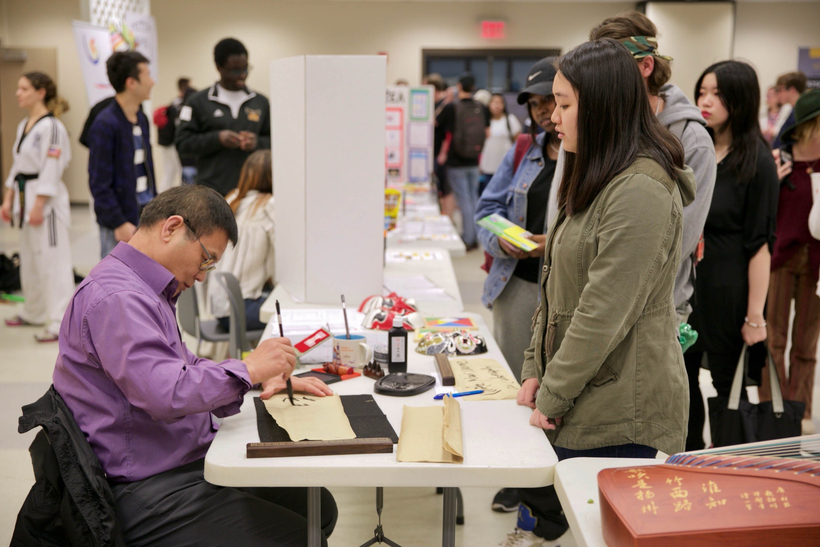 A student watches Dr. Louis Liuxi Meng practice Chinese calligraphy during Foreign Language Day on March 21. Photo credit: Felix Amaya