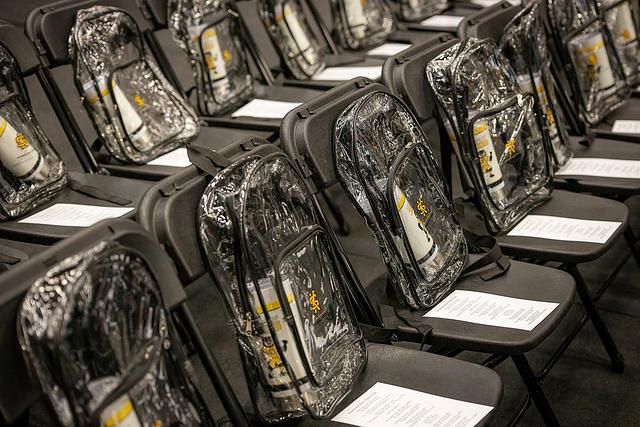Rows of chairs with clear backpacks and documents placed on them.