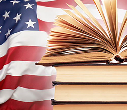 A collection of books positioned in front of an American flag, representing education and national pride.