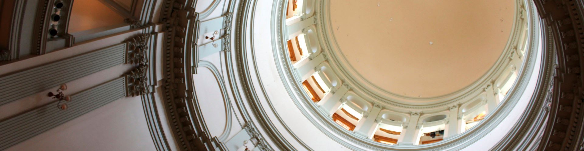 The interior dome of a historic building with columns and decorative molding