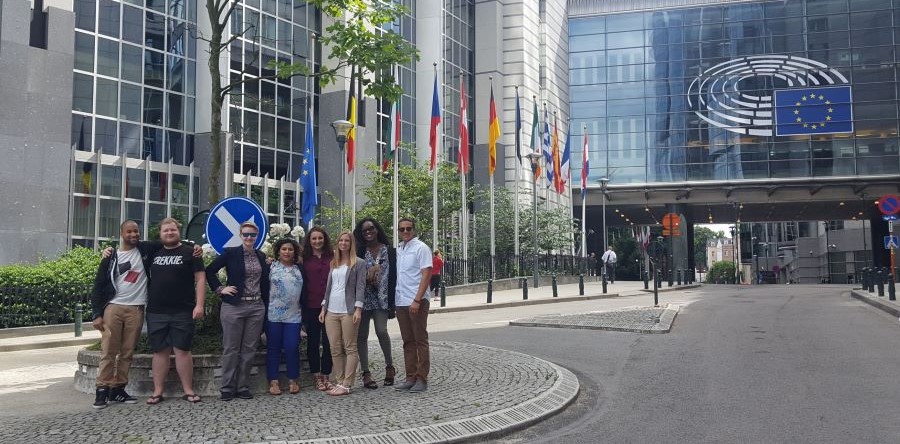 Group of people posing outside a building with European flags.
