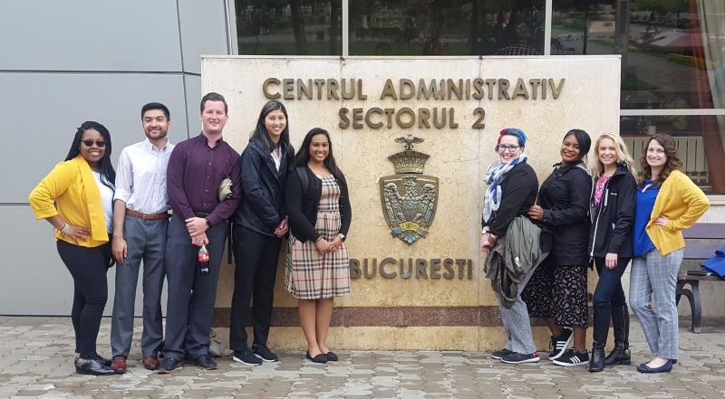 Group of students posing in front of a sign reading 'Centrul Administrativ Sectorul 2 Bucuresti' in Romania.