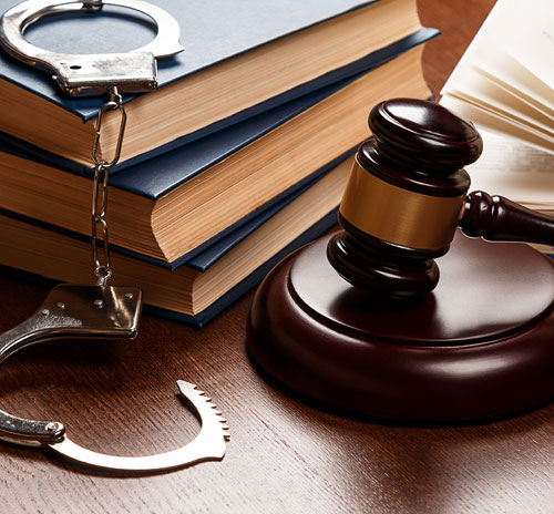 A desk featuring a stack of legal documents and handcuffs, symbolizing criminal law and justice.